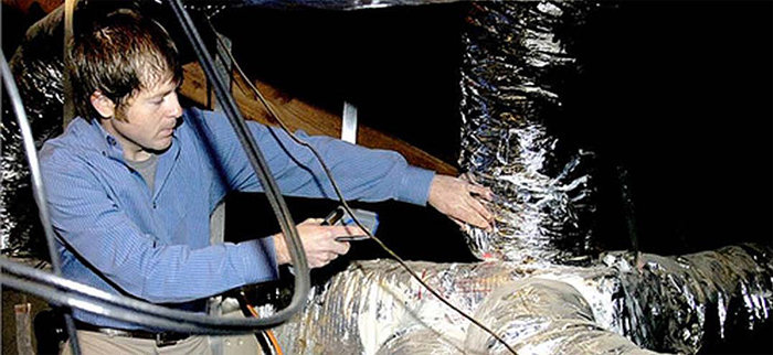 Energy auditor checking insulation around pipes (Photo courtesy of United Cooperative Services)