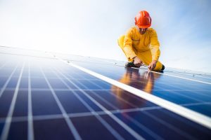 Person wearing protective clothing installing solar panels.