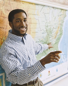 A man pointing to a map of the United States in a classroom