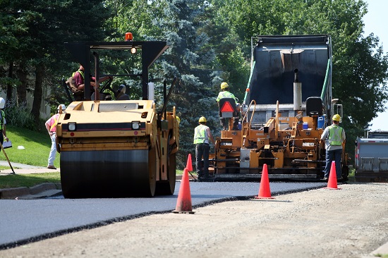 Construction workers using an asphalt spreader