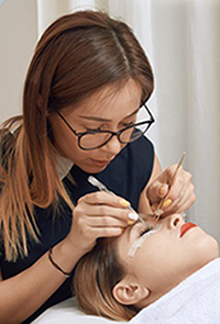 Beautician applying fake eyelashes to a customer