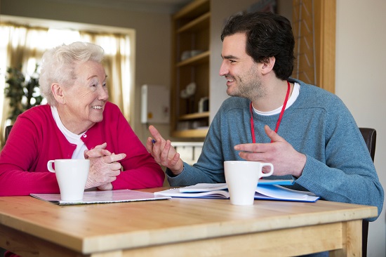 Male social worker helps older woman with paperwork