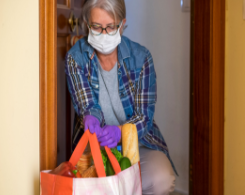 Woman wearing face mask with bag of groceries