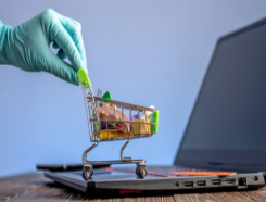Gloved hand, shopping cart, and laptop computer