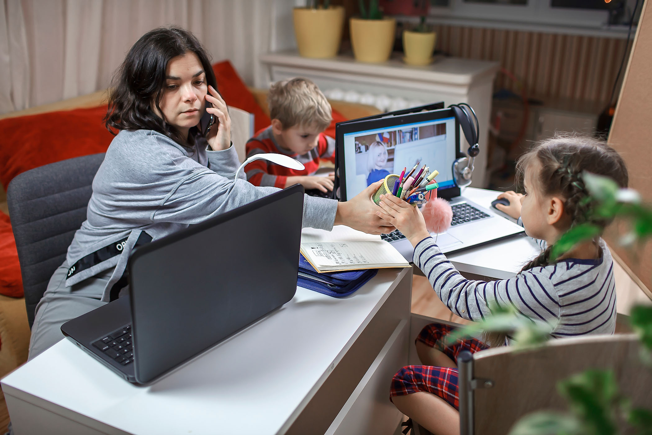 Photo of a woman and children all working at laptop computers