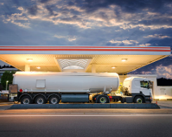 Gasoline tanker truck delivering gasoline to gas station.
