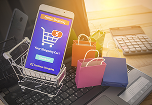 Illustration of a smartphone with a shopping app open inside a shopping cart. Illustration also includes gift bags and consumer items such as a keyboard and calculator.