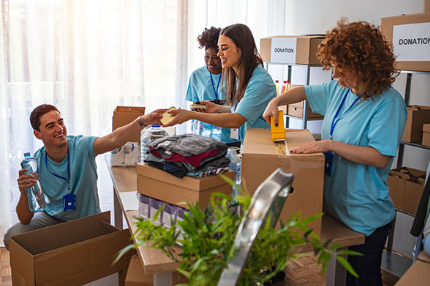 Four nonprofit office workers packing donations into boxes. 