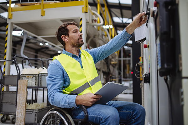 Photo of a man in a wheelchair working on industrial equipment