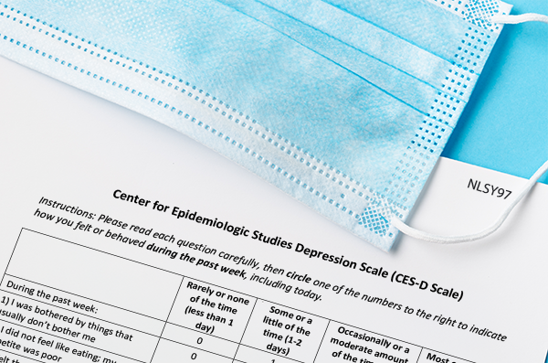 Survey questionnaire paperwork on a table with a blue medical mask laying on top.
