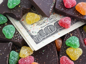 A 100-dollar bill sits below gumdrops and chocolate.
