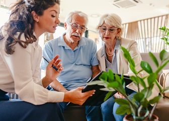 An older couple talks with a concierge who is assisting them with a hotel offer.