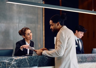 A man registering with the assistance of a front desk concierge.