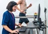 A cardiovascular technician looking at a computer screen while a patient walks on a treadmill during a stress test