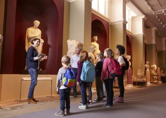 A tour guide speaking to children in a museum