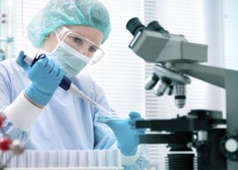 A woman in a laboratory wears safety equipment such as goggles and gloves.