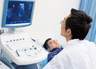 Diagnostic medical sonographer looking at an image on a computer