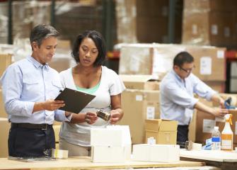 Male and female logisticians talking in warehouse.