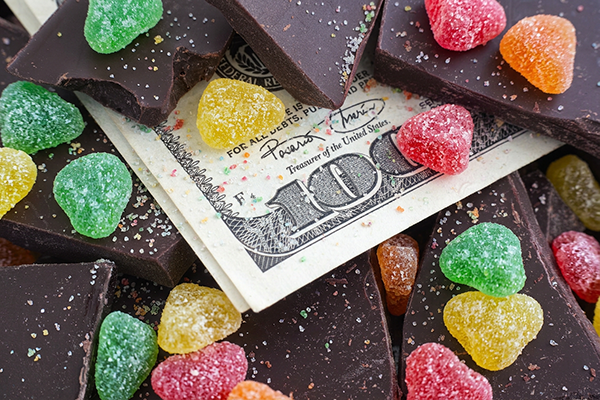 A 100-dollar bill sits below gumdrops and chocolate.