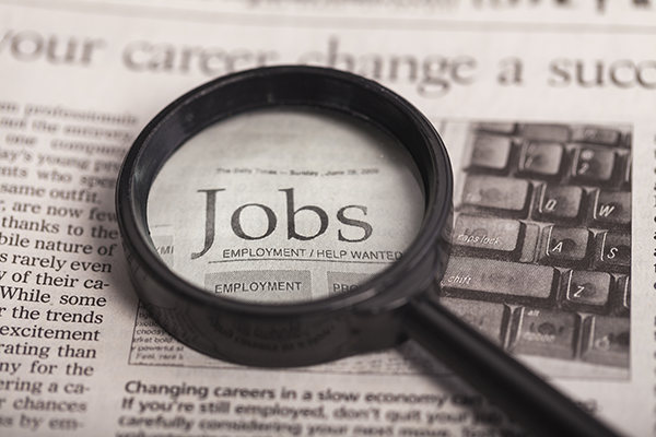Magnifying glass looking at a newspaper closely with the word "jobs" underneath it