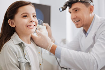 Medical professional performing ear exam on a child.