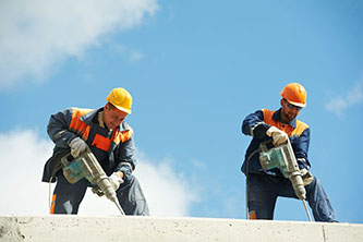 Two construction workers using cement drills.