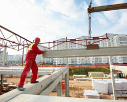 Construction worker helping move large beam