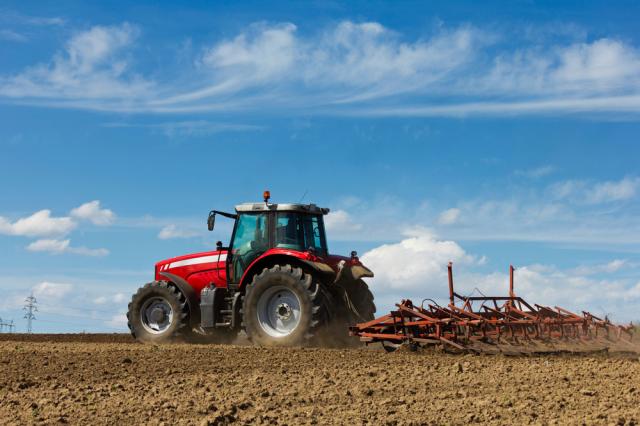 Worker on tractor tilling land