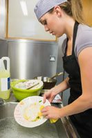 Person manually washing dishes in a restaurant kitchen