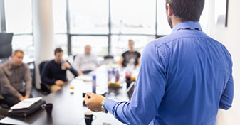 Male human resources specialist speaking to a group of employees sitting at a table.