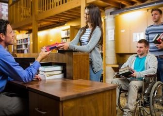 Librarian at a desk receiving books from library patrons.