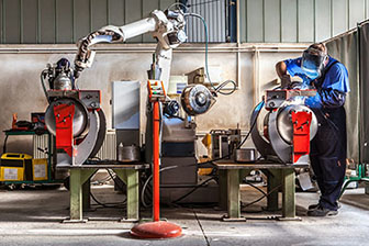 Man welding and robotic arm.