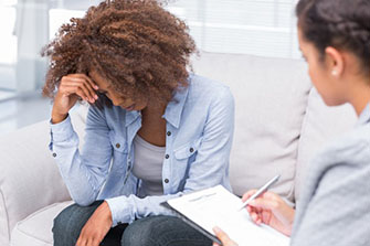 Mental health professional with clipboard and pen listening to patient.