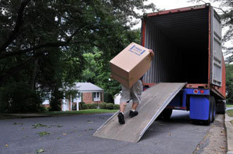 Worker using ramp to place box on truck