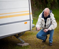 Man crouching while lowering a jack at the rear of a travel trailer