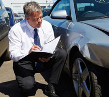 Worker bending to assess car damage