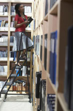 Worker ascending ladder to bookshelf