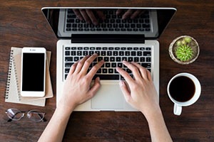 Looking down at two hands typing on a laptop keyboard